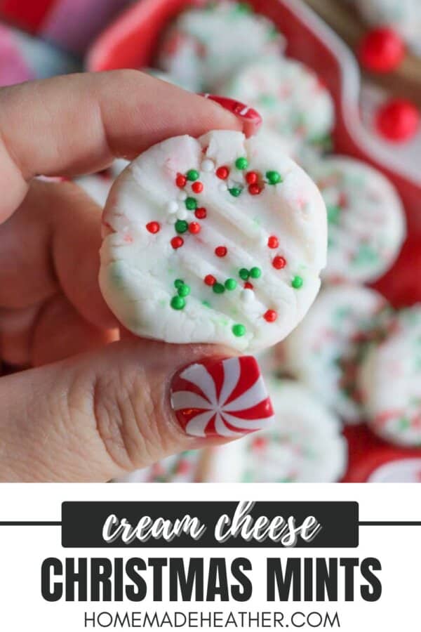 A close-up of a hand holding a cream cheese mint decorated with red and green sprinkles. The person has a peppermint nail design. The text reads, Cream Cheese Christmas Mints homemadeheather.com.