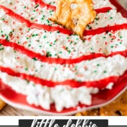 A festive bowl of Christmas cake dip topped with red icing, green and red sprinkles, and a pretzel piece on a red plate. The text reads Little Debbie Christmas Cake Dip and homemadeheather.com.
