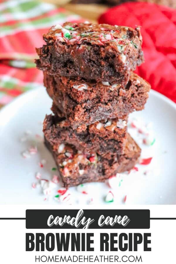 A stack of candy cane brownies on a white plate, topped with crushed candy cane pieces, with a festive red and green background. Text reads Candy Cane Brownie Recipe - homemadeheather.com.