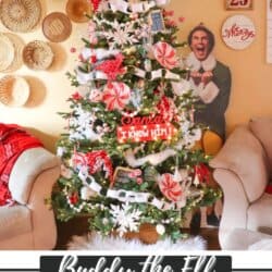 A Christmas tree decorated with red and white candy ornaments, snowflakes, and greenery. It features a cardboard cutout of Buddy the Elf next to it. The room has beige walls with baskets and a decorative sign.