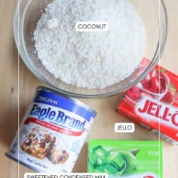 A bowl of shredded coconut, a can of sweetened condensed milk, and two Jell-O boxes (strawberry and lime) are displayed on a wooden surface, hinting at more than just desserts—with a twist reminiscent of a thin mint cookie recipe. Labels identify the coconut, Jell-O, and condensed milk.