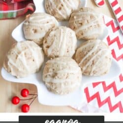 A star-shaped plate holds six eggnog cookies drizzled with icing. The plate is on a wooden surface with festive red berries, a candy cane, and a red and green cloth nearby. Text reads Eggnog Cookie Recipe - homemadeheather.com.