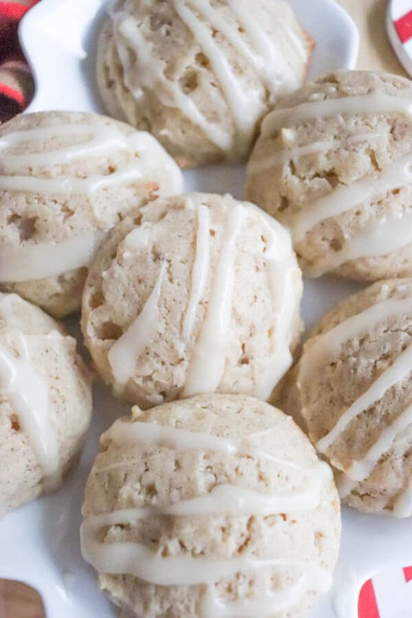 Eggnog Cookie Recipe A plate of iced cookies drizzled with white icing, showcasing a golden-brown color and a round, textured appearance. The cookies are closely arranged, highlighting their icing pattern and inviting presentation.