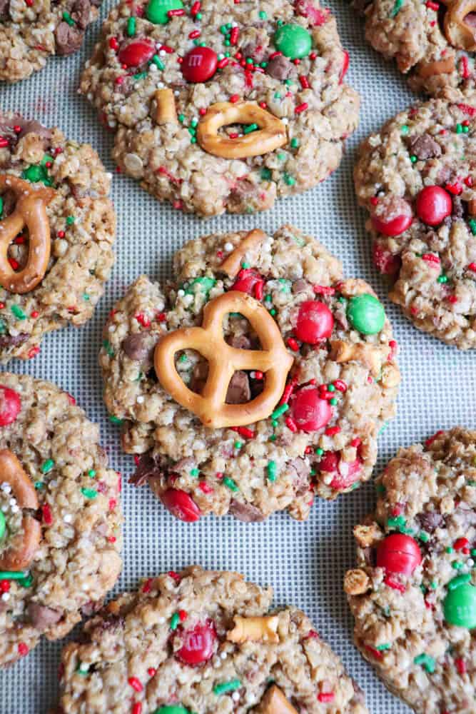 A close-up of colorful, festive Christmas cookies on a tray. These kitchen sink delights are topped with red and green candies, pretzels, and sprinkles, creating a cheerful holiday appearance.