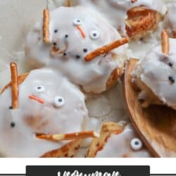 Glazed cinnamon rolls decorated as snowmen with candy eyes, pretzel stick arms, and orange candy noses in a baking dish. Text at the bottom reads Snowman Cinnamon Rolls homemadeheather.com.