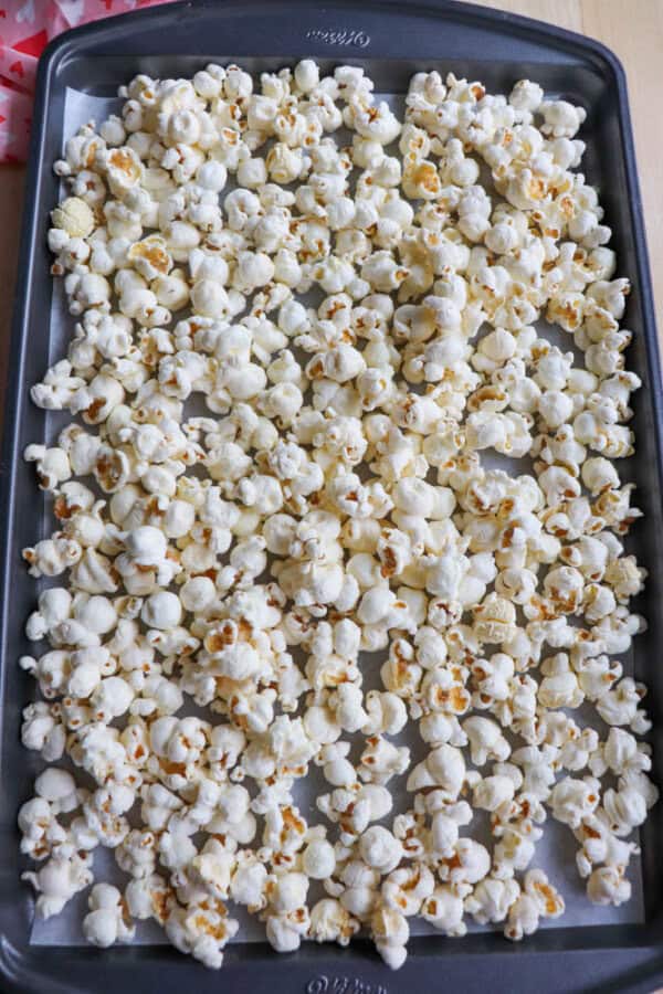 A baking tray filled with freshly popped popcorn evenly spread out.