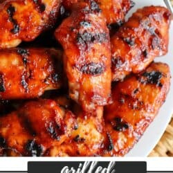 A plate of grilled BBQ chicken wings glistening with sauce. The wings are charred in places, giving them a rich, smoky appearance. Text below reads, Grilled BBQ Chicken Wings homemadeheather.com.