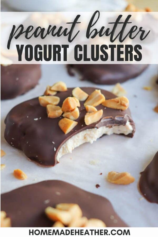 Close-up of peanut butter yogurt clusters topped with chocolate and chopped peanuts. One cluster has a bite taken out, showing the creamy yogurt inside. Text at the top reads โpeanut butter yogurt clusters.โ.