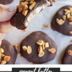 A hand holding a bitten peanut butter yogurt cluster, covered in chocolate and topped with chopped peanuts, over a background of similar clusters on a baking sheet. Text at the bottom reads peanut butter yogurt clusters homemadeheather.com.