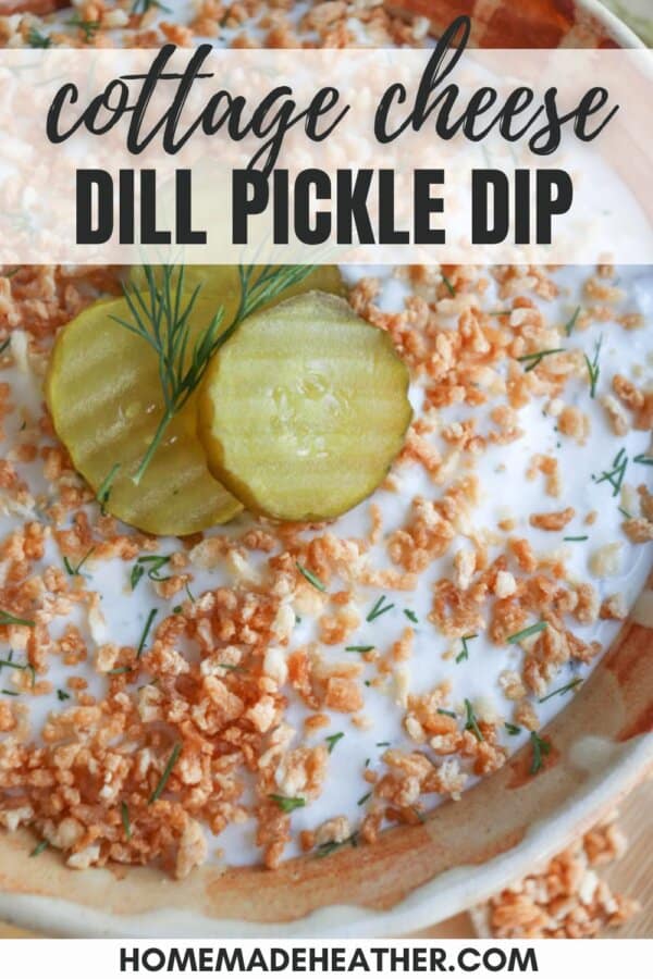 A close-up of cottage cheese dill pickle dip topped with crispy bits, dill sprigs, and pickle slices. Text at the top reads cottage cheese dill pickle dip. The bottom shows homemadeheather.com.
