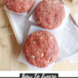 Three raw hamburger patties on parchment paper are arranged on a wooden surface. Text at the bottom reads how to freeze hamburger patties with a URL to homemakeheather.com.