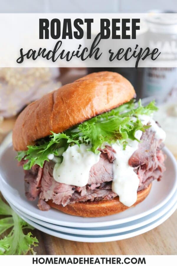 A roast beef sandwich on a plate with lettuce and creamy sauce, served on a glazed bun. The background includes a blurred out ingredient or condiment container. Text on the image reads: Roast Beef Sandwich Recipe and homemadeheather.com.