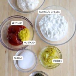 Top-down view of ingredients for a recipe on a wooden surface. Includes bowls of mayo, cottage cheese, ketchup, mustard, pickles, sugar, and seasoning, each labeled.