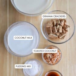 An overhead view of five labeled bowls on a wooden surface: vanilla protein shake, graham crackers, coconut milk, toasted coconut, pudding mix, and vanilla extract. Text at the bottom reads homemadeheather.com.