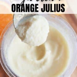 A close-up of a creamy, orange-colored dessert in a blender cup. A spoon holds a scoop above the cup. Text on the image reads Copycat High Protein Ninja Creami Orange Julius Recipe and homemadeheather.com.