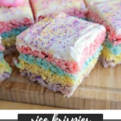 Colorful layered Rice Krispies treats with pink, blue, yellow, and purple layers, topped with white frosting and purple sprinkles, displayed on a wooden surface. Text reads Rice Krispies Easter Peeps Treats homemadeheather.com.