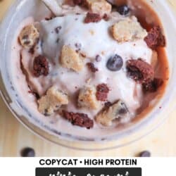 A bowl of ice cream topped with chunks of cookie dough and brownie pieces, with a spoon resting in it. Text reads Copycat High Protein Ninja Creami Half Baked Ice Cream HomemadeHeather.com at the bottom.