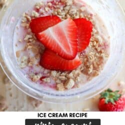 Top view of strawberry cheesecake ice cream in a bowl, garnished with sliced strawberries and crumbled crust. Text on the image reads: Ice Cream Recipe Ninja Creami Strawberry Cheesecake homemadetheather.com. A whole strawberry is visible on the side.