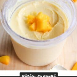 A creamy mango frozen yogurt served in a clear container, topped with small mango chunks. The background features more mango pieces and a small white bowl. Text at the bottom reads ninja creami MANGO FROYO.