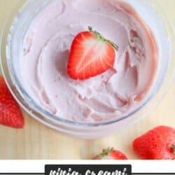 A bowl of pink strawberry frozen yogurt topped with a half strawberry. Several whole strawberries are scattered around it. Text on the bottom reads: ninja creami STRAWBERRY FROYO homemadeheather.com.