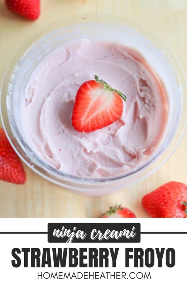 A bowl of pink strawberry frozen yogurt topped with a half strawberry. Several whole strawberries are scattered around it. Text on the bottom reads: ninja creami STRAWBERRY FROYO homemadeheather.com.