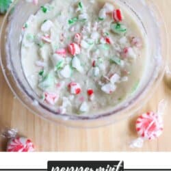 A bowl of homemade peppermint ice cream with crushed peppermint candies on top. Surrounding the bowl are unwrapped peppermint candies on a wooden surface. Text at the bottom reads, Peppermint Ninja Creami Ice Cream homemadetheather.com.