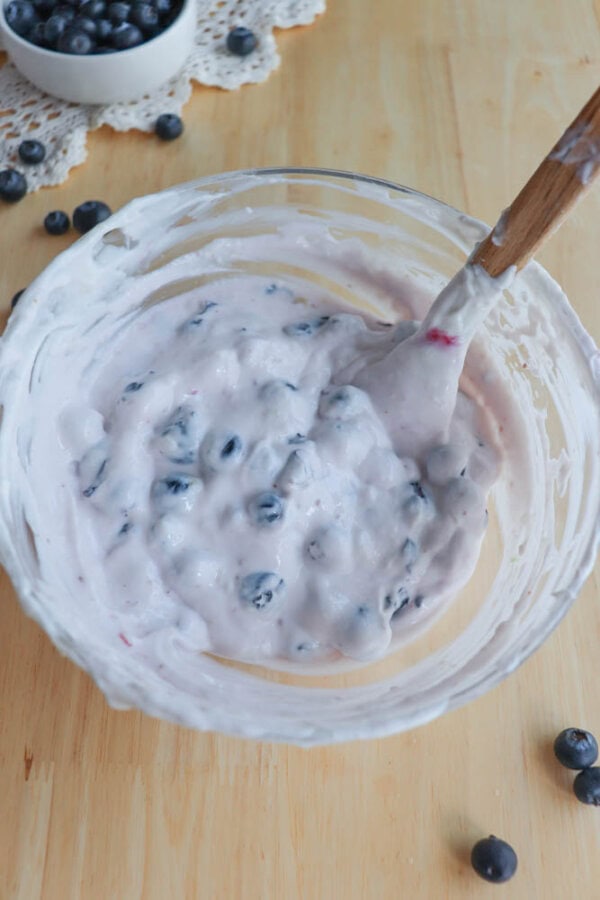 Blueberries and yogurt mixed together in a glass bowl.