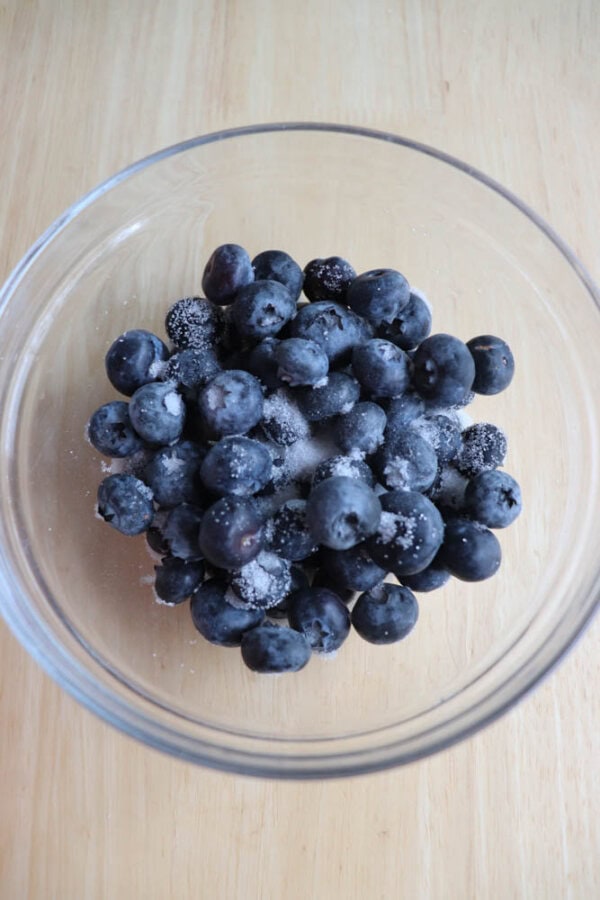 A bowl of fresh blueberries on a wooden table.