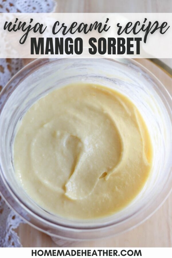 A bowl of creamy mango sorbet with a smooth texture, set on a wooden surface. The top text says ninja creami recipe MANGO SORBET and the bottom text reads HOMEMADEHEATHER.COM. Theres a hint of lace in the background.