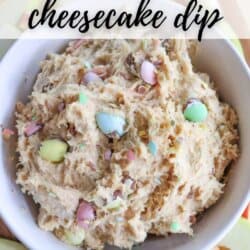 A bowl of mini egg cheesecake dip, topped with colorful candy-coated chocolate eggs. Around the bowl are slices of green and red apples for dipping. Text on the image reads Mini Egg Cheesecake Dip at the top and homemadeheather.com at the bottom.