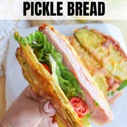 A hand holds a sandwich made with pickle bread, filled with ham, lettuce, and tomatoes. The image features text that reads 2-ingredient pickle bread and homemadeheather.com at the bottom.