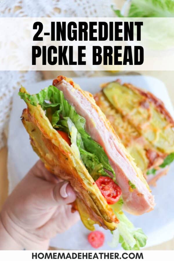 A hand holds a sandwich made with pickle bread, filled with ham, lettuce, and tomatoes. The image features text that reads 2-ingredient pickle bread and homemadeheather.com at the bottom.
