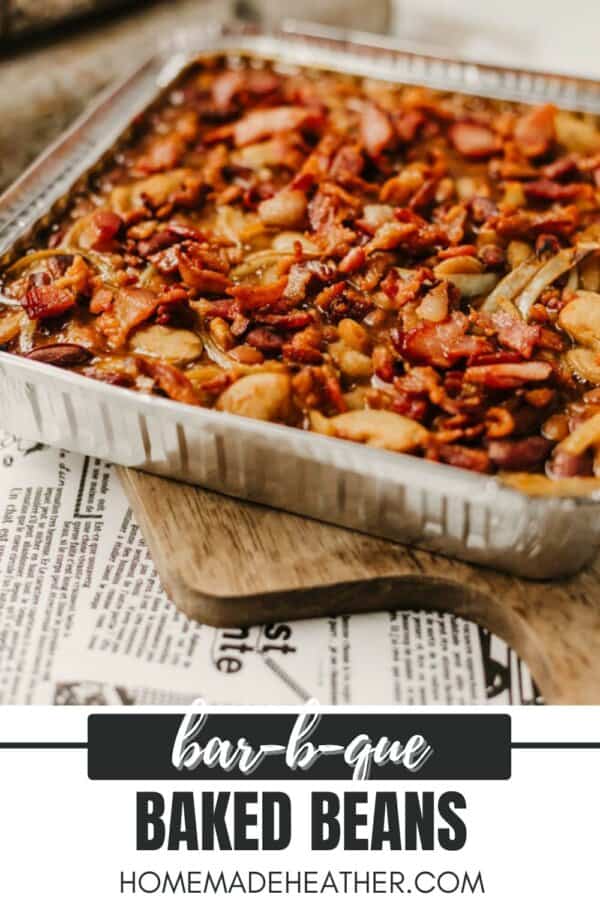 A foil tray filled with barbecued baked beans, topped with bacon, sits on a wooden board. Text on the image reads bar-b-que BAKED BEANS and homemadeheather.com.