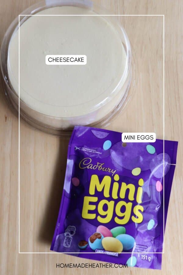 A round cheesecake in a pan is on a wooden surface. Next to it is a purple bag of Cadbury Mini Eggs. The bag is slightly open, showing the candy inside. The words CHEESECAKE and MINI EGGS are labeled on the image.