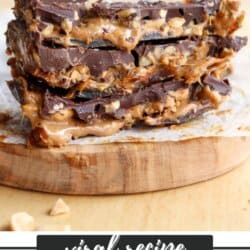 A stack of Snickers Date Bars is placed on a wooden surface. The bars have layers of chocolate, peanut butter, and nuts. Text reads viral recipe at the top and SNICKERS DATE BARS at the bottom with the website homemadeheather.com.