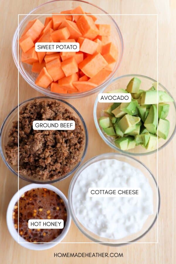 Top view of five bowls containing different ingredients on a wooden surface. The bowls are labeled: sweet potato, avocado, ground beef, cottage cheese, and hot honey. Website text reads homemadeheather.com at the bottom.