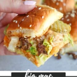 A hand holding a mini sandwich made with a sesame seed bun, ground beef, lettuce, cheese, pickles, and sauce. Other similar sliders are visible in the background. Text reads: Big Mac Sliders Recipe, homemadeheather.com.