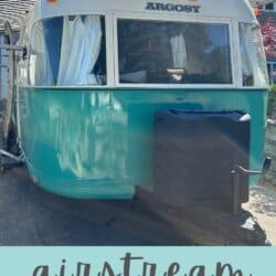 A restored Argosy Airstream trailer from 1975 with teal and white paint is parked in a driveway. White curtains hang in the windows. Text reads: โairstream argosy 1975 restoration homemadetheather.comโ.