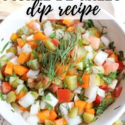 A white bowl filled with colorful pickle de gallo dip, made of diced pickles, onions, tomatoes, peppers, and herbs, garnished with a sprig of dill. Text reads Pickle de Gallo dip recipe and homemadeheather.com.
