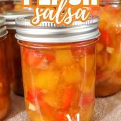 A glass jar filled with homemade peach salsa, showing chunks of peaches, tomatoes, and onions. Other similar jars sit in the background. Text on the image reads Peach salsa, so good! and homemadeheather.com.