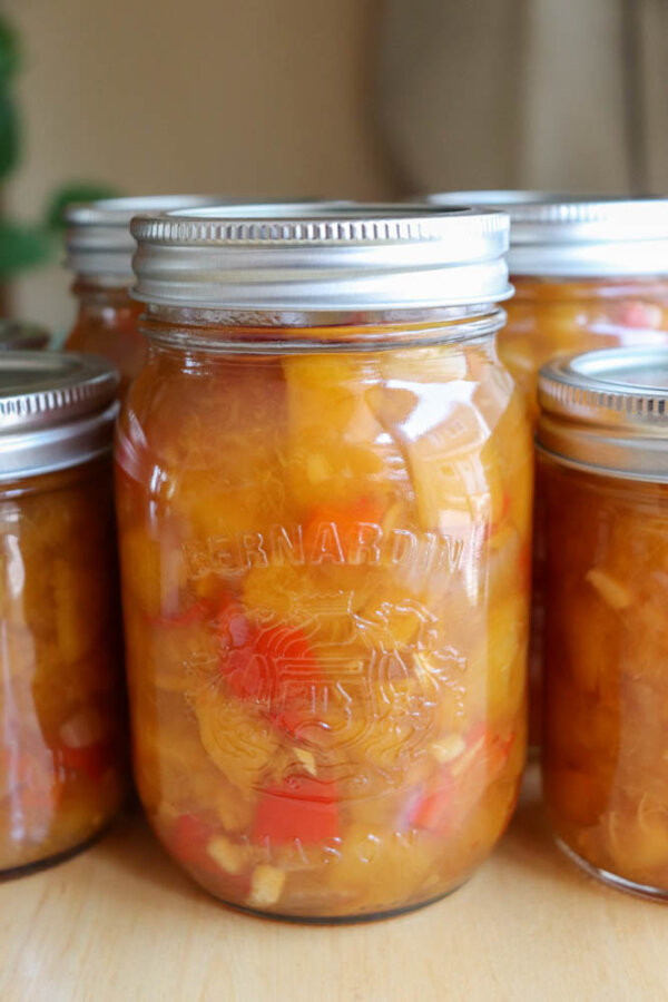 A close-up of glass jars filled with homemade chutney or preserved fruit, featuring chunks of yellow and red pieces, sealed with metal lids and labeled Bernardin.