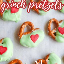 A close-up of pretzels dipped in green coating, each decorated with a red heart candy, arranged on a white surface. Large text reads “CHRISTMAS grinch pretzels” and “SO EASY!” at the bottom.