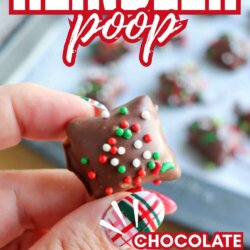 A hand with festive red and white plaid nail art holds a chocolate-covered peanut butter pretzel topped with holiday sprinkles. In the background, more pretzels rest on a baking sheet. Text reads: Reindeer Poop: Chocolate Covered PB Pretzels.