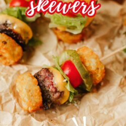 Mini cheeseburger skewers with tater tots, lettuce, tomato, and cheese on parchment paper. Text overlay reads: “CHEESEBURGER skewers SO FUN!” and “homemadeheather.com” at the bottom.