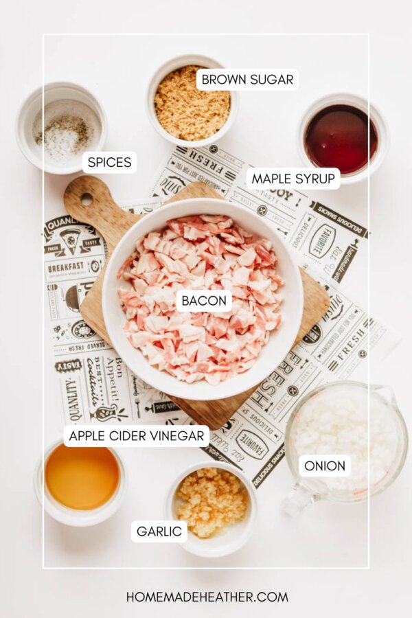 Top-down view of small bowls containing chopped bacon, brown sugar, maple syrup, diced onion, minced garlic, apple cider vinegar, and spices, all labeled, on a white background with a printed mat.