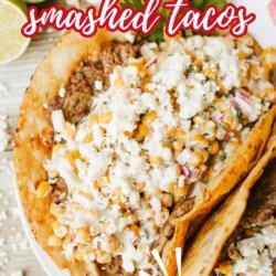 Two tacos on a white plate are topped with seasoned meat, street corn, cheese, and sauce. Text over the image reads, Street Corn Smashed Tacos - The Best Smashup! and homemadeheather.com at the bottom.