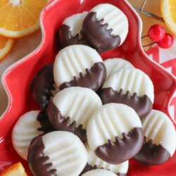A red star-shaped plate holds round white cookies half-dipped in chocolate, surrounded by orange slices on a red-and-white patterned surface. The text reads, Chocolate Orange Creams and homemadeheather.com.