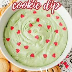 A bowl of light green dip topped with red heart sprinkles, surrounded by cookies. Text reads Grinch cookie dip—so easy! with homemadeheather.com at the bottom.
