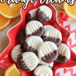 A star-shaped red dish holds round, white chocolate-dipped orange cream cookies with fork marks. Orange slices and a festive napkin are nearby. Text reads: โChocolate Dipped Orange Creams, NO BAKE, homemadeheather.com.โ.
