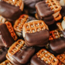 A plate of square pretzels filled with peanut butter and half-dipped in chocolate. Text on the image reads Buckeye pretzels and homemadeheather.com.